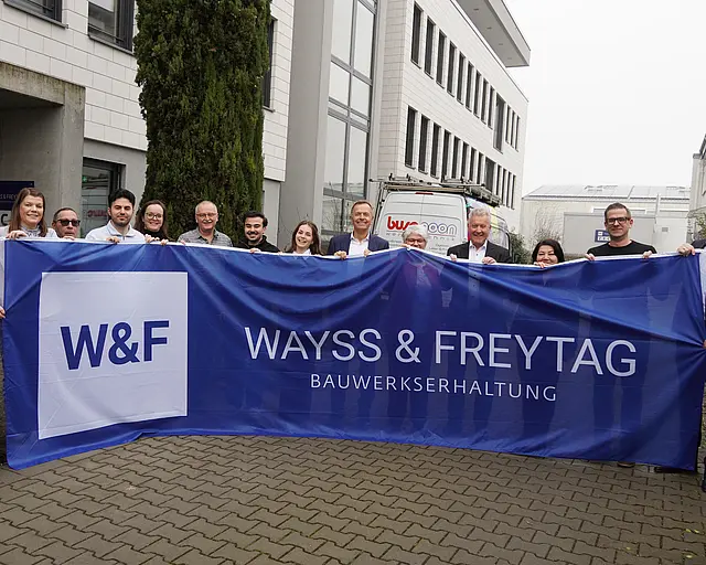 Mehrere Menschen halten eine blaue W&F Flagge hoch.