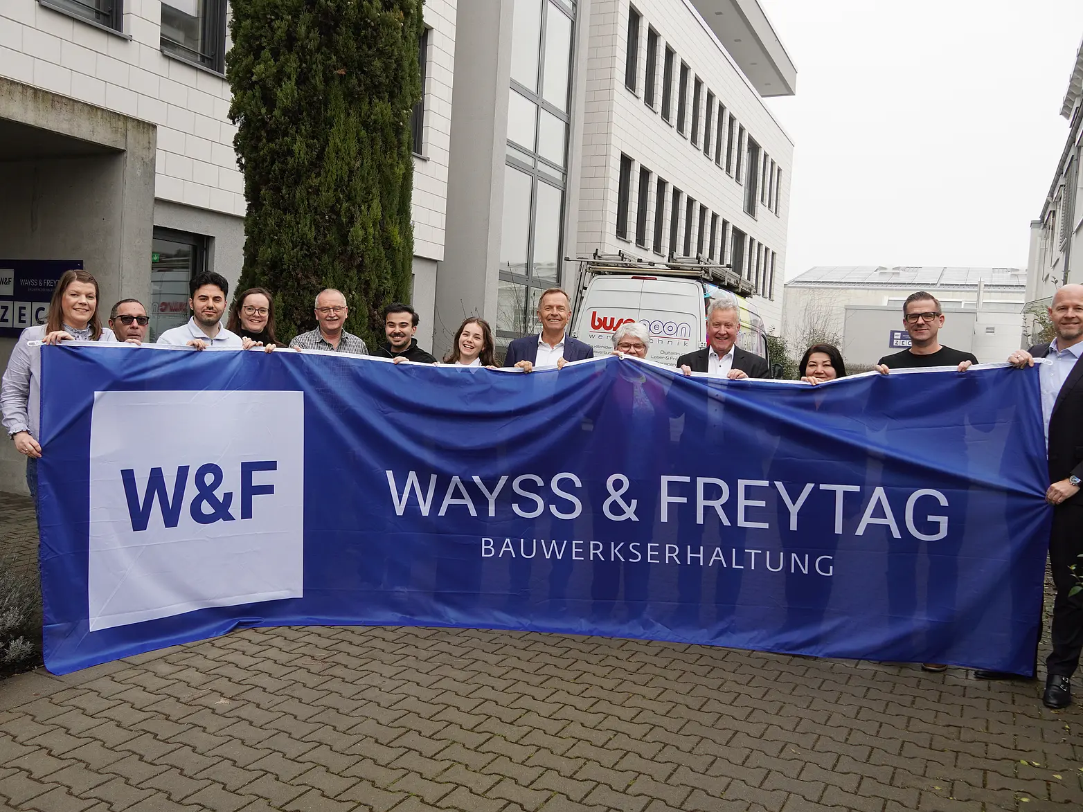 Mehrere Menschen halten eine blaue W&F Flagge hoch.
