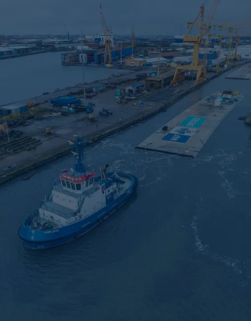 Ein Tunnelelement wird von einem Boot über Wasser gezogen. 