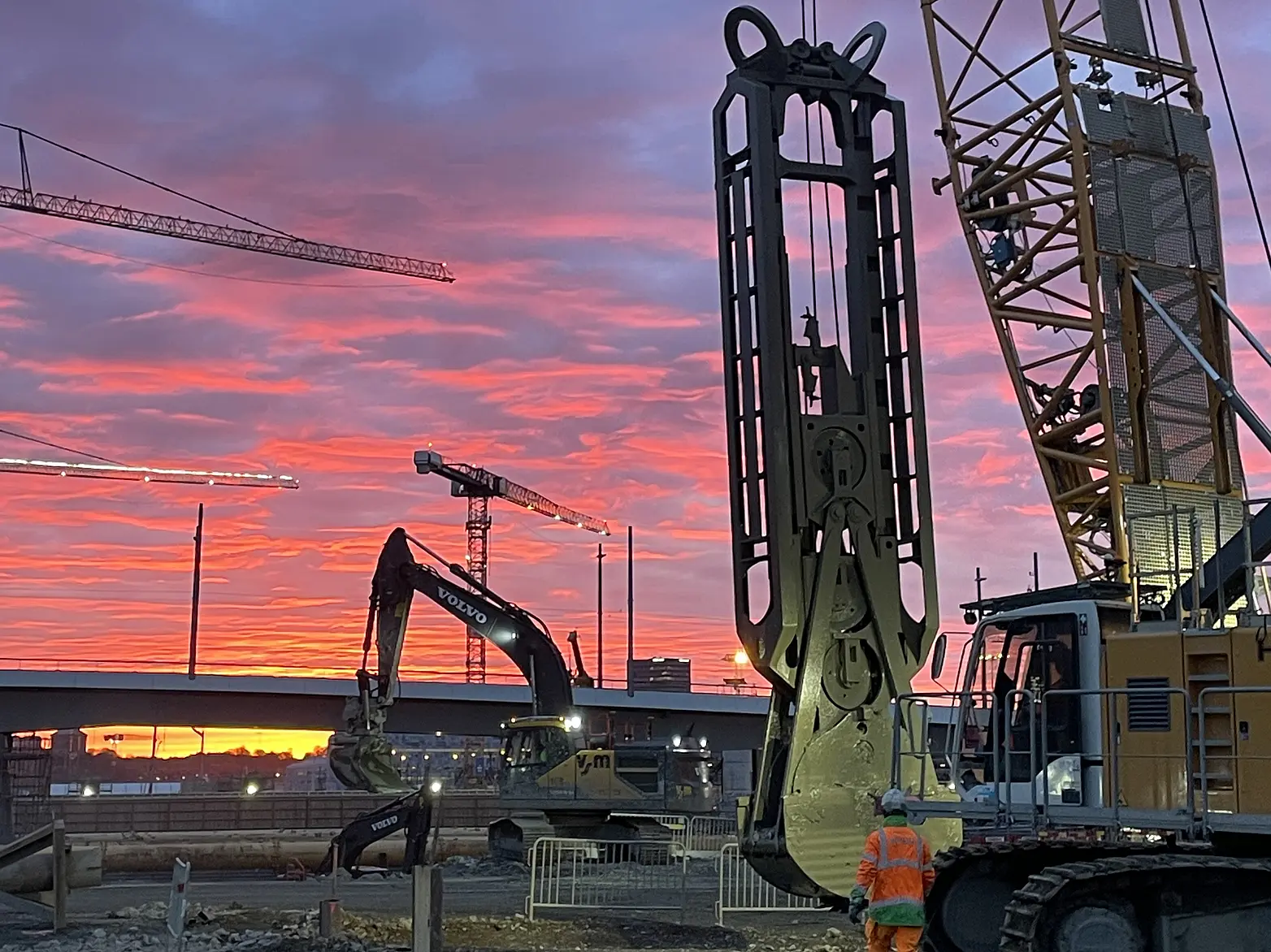 Eine Baustelle in rosa Licht getaucht, im Vordergrund ist ein Schlitzwandgreifer zu sehen