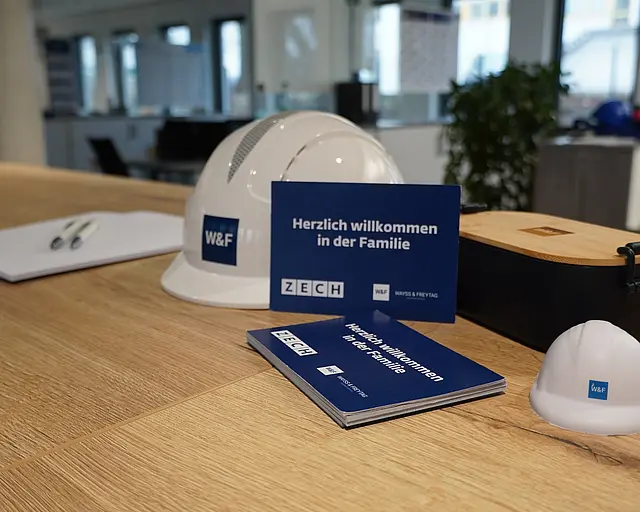 Auf einem Regal liegt ein W&F Helm und eine Willkommenskarte.