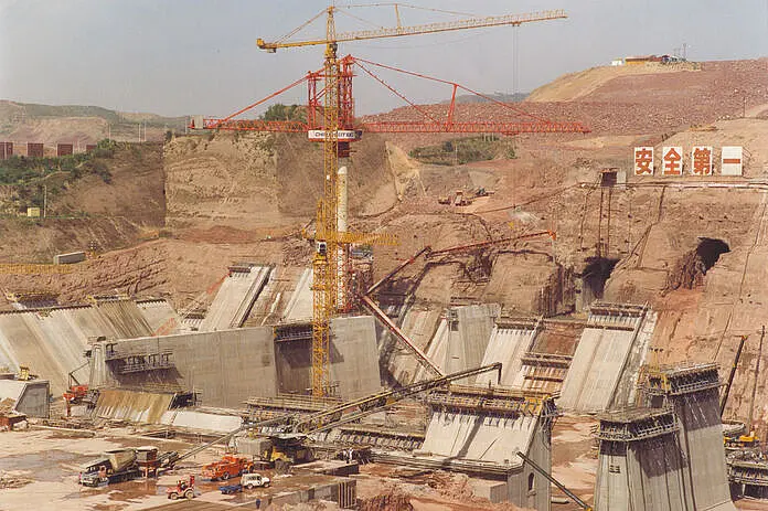 Ein Kran auf einer Baustelle umgeben von braunen Gestein und Sand.