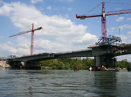 Zwei Kräne im Hintergrund, davor eine Brücke.