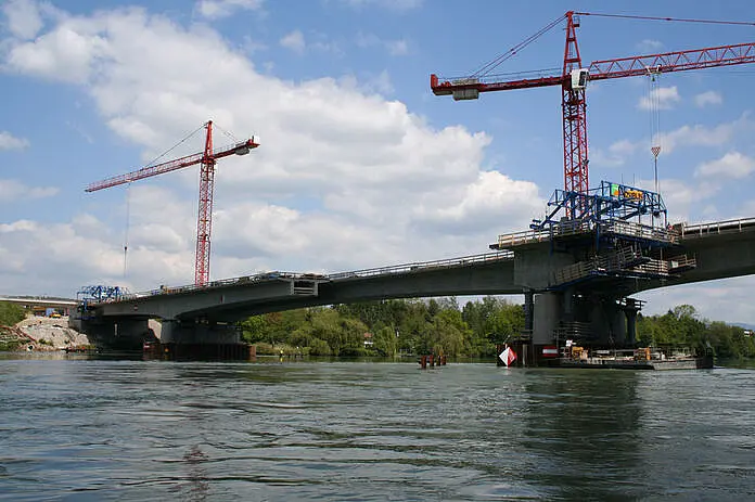 Zwei Kräne im Hintergrund, davor eine Brücke.