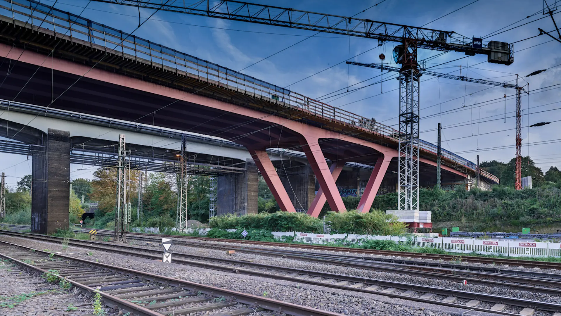 Eine rote Brücke über Gleisen.
