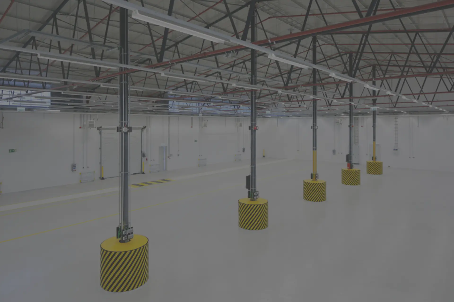 Eine Halle mit weißen Wänden und Boden und Pfeilern, die auf einer gelb-schwarz gestreiften Sohle stehen