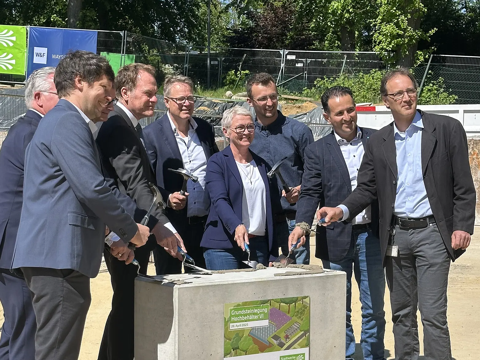 Eine Gruppe Beteiligter posiert für ein Foto zur Grundsteinlegung. 