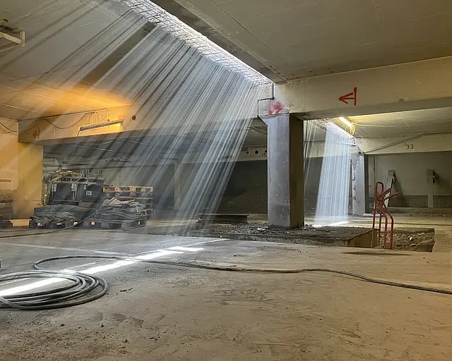 Durch die Decke einer Tiefgarage schimmert ein Lichtstrahl.