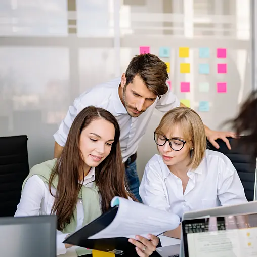 Drei Personen reden im Büro miteinander.