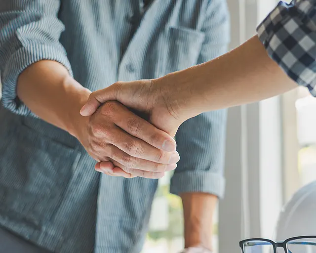 Zwei Personen geben sich die Hand.
