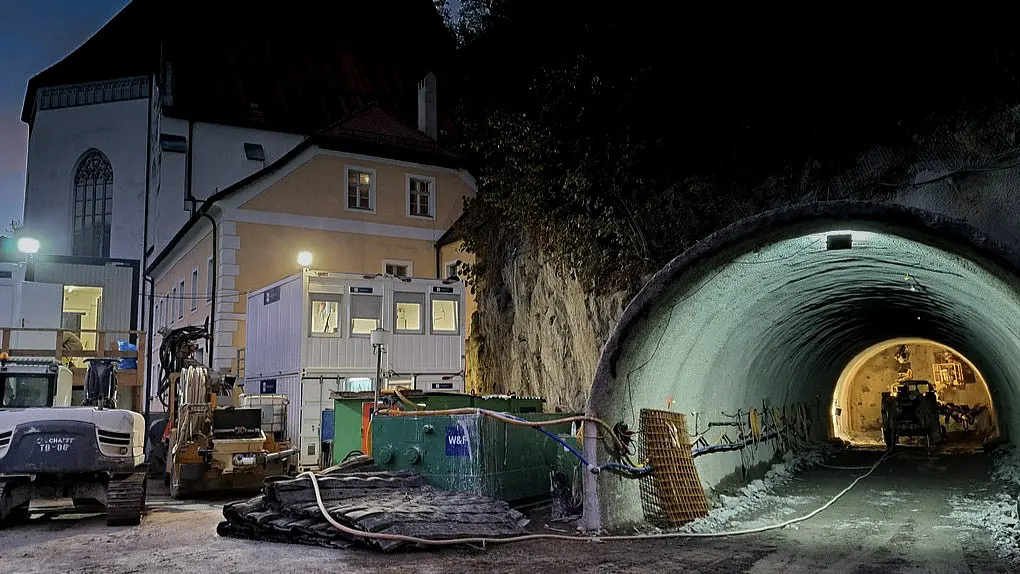 Tunneleingang in einen beleuchteten Tunnel.